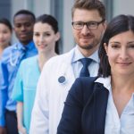 Portrait of smiling doctors standing in row at hospital premises